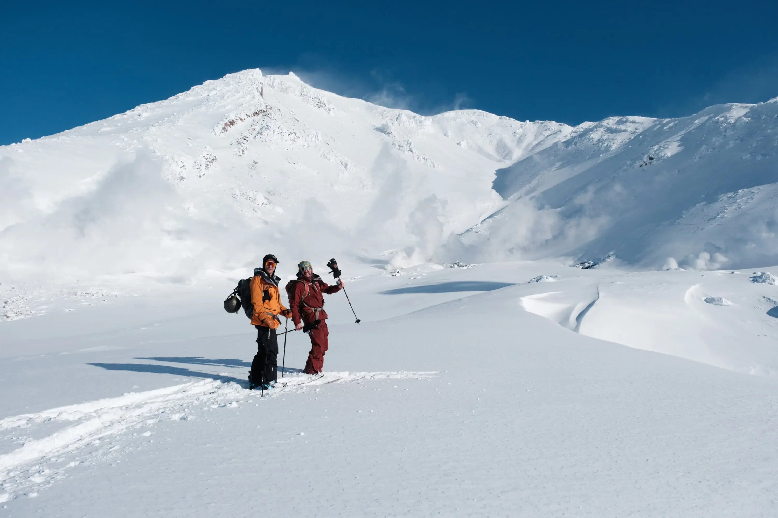 Two backcountry skiers below a snowy volcanic peak in Central Hokkaido