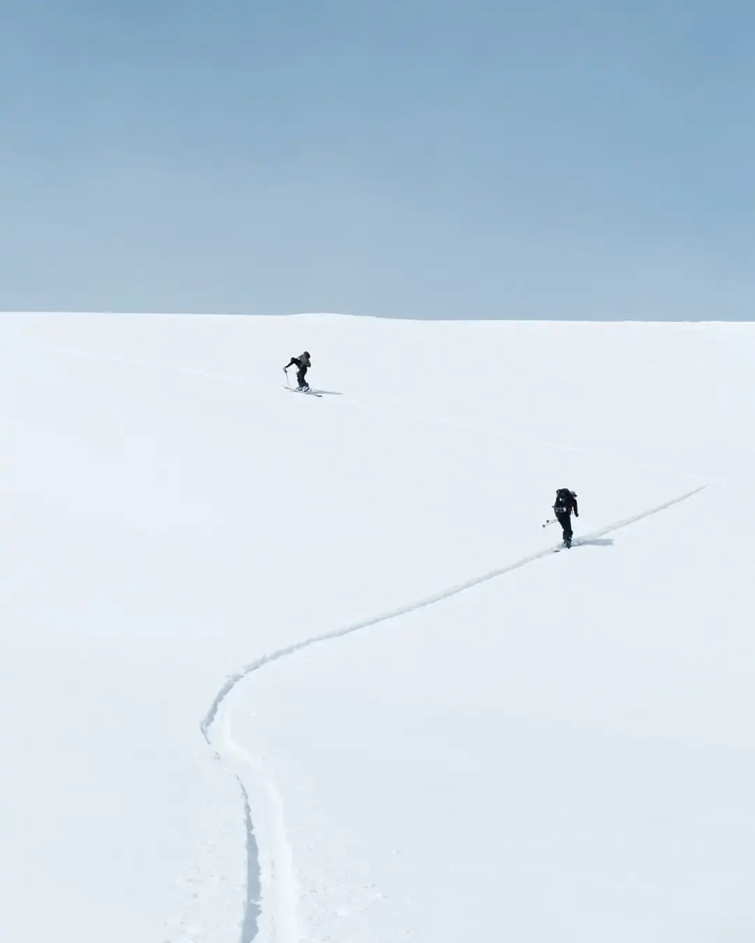 April touring in the sunshine Two ski tourers on a wide open snowfield in spring