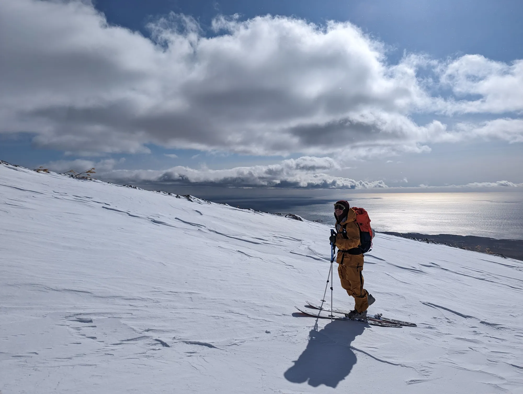 Ski tourer climbing Mount Rishiri with the Sea of Japan far below, Rishiri Island, Hokkaido